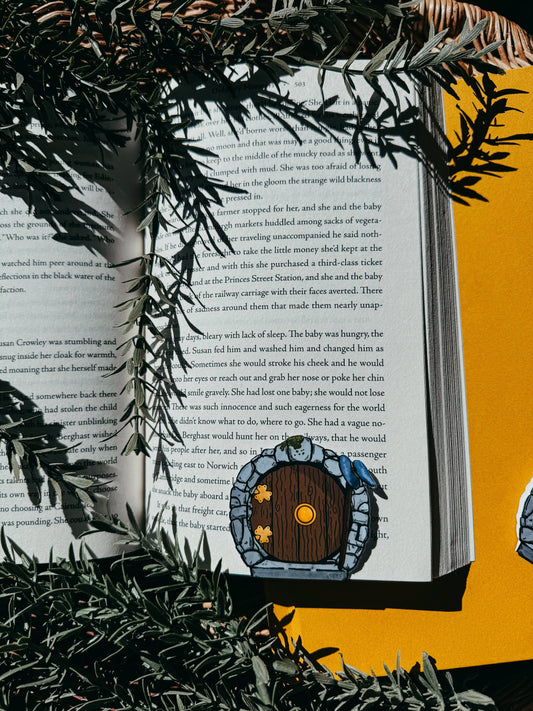 Open book with a hobbit hole illustration on a yellow background