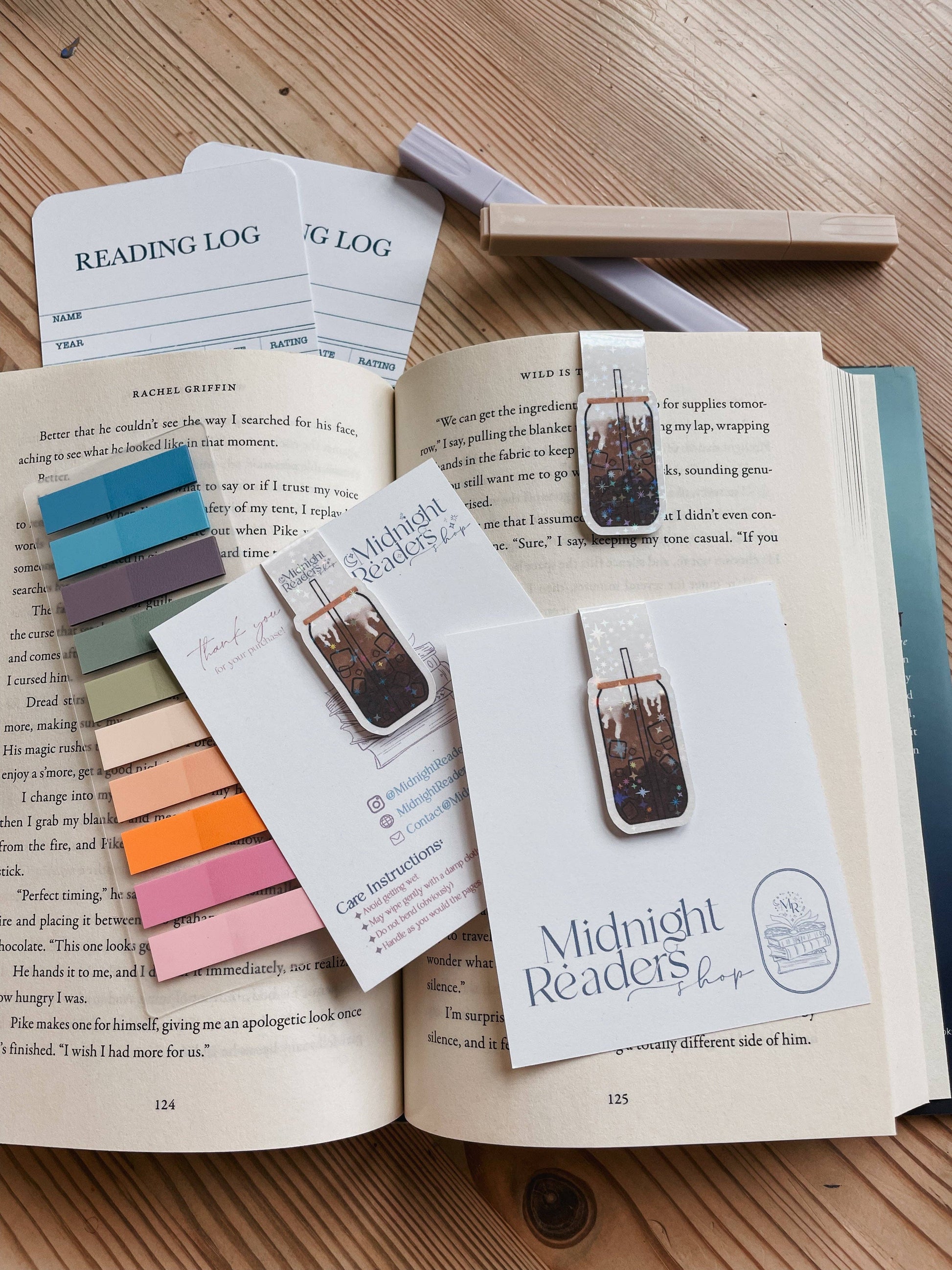 Open book with bookmarks, color swatches, and a reading log on a wooden surface