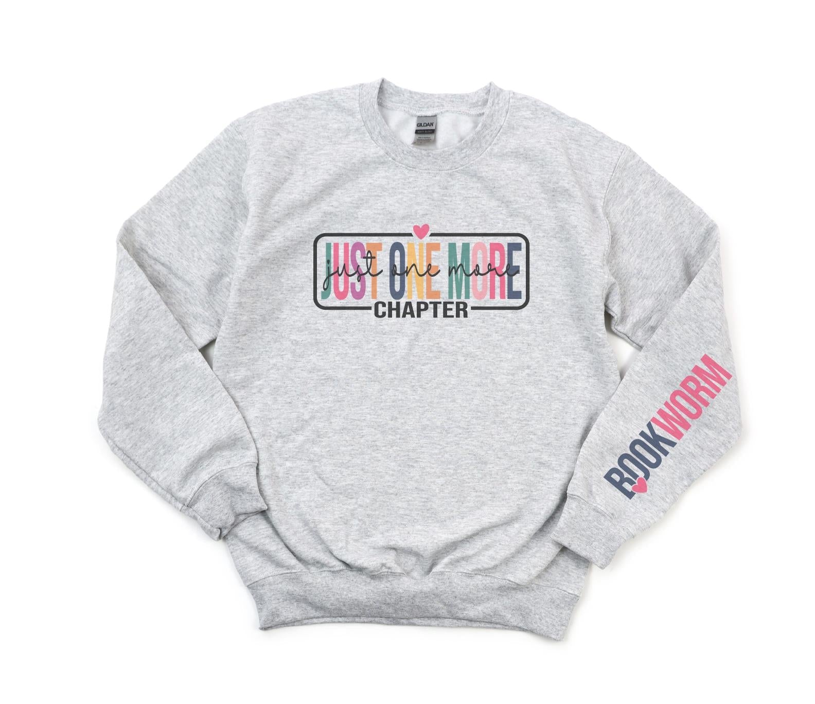 Gray sweatshirt with 'Just One More Chapter' and 'Bookworm' text on a white background
