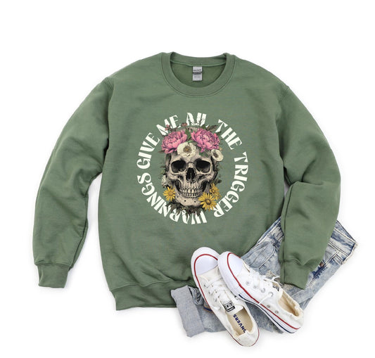Green sweatshirt with skull and floral design, paired with white sneakers and gray pants on a white background.
