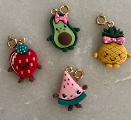 Set of colorful fruit-shaped charms on a gray surface
