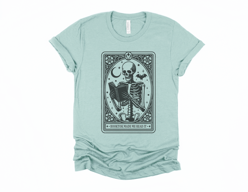 Light blue t-shirt with a skeleton and book graphic on a white background
