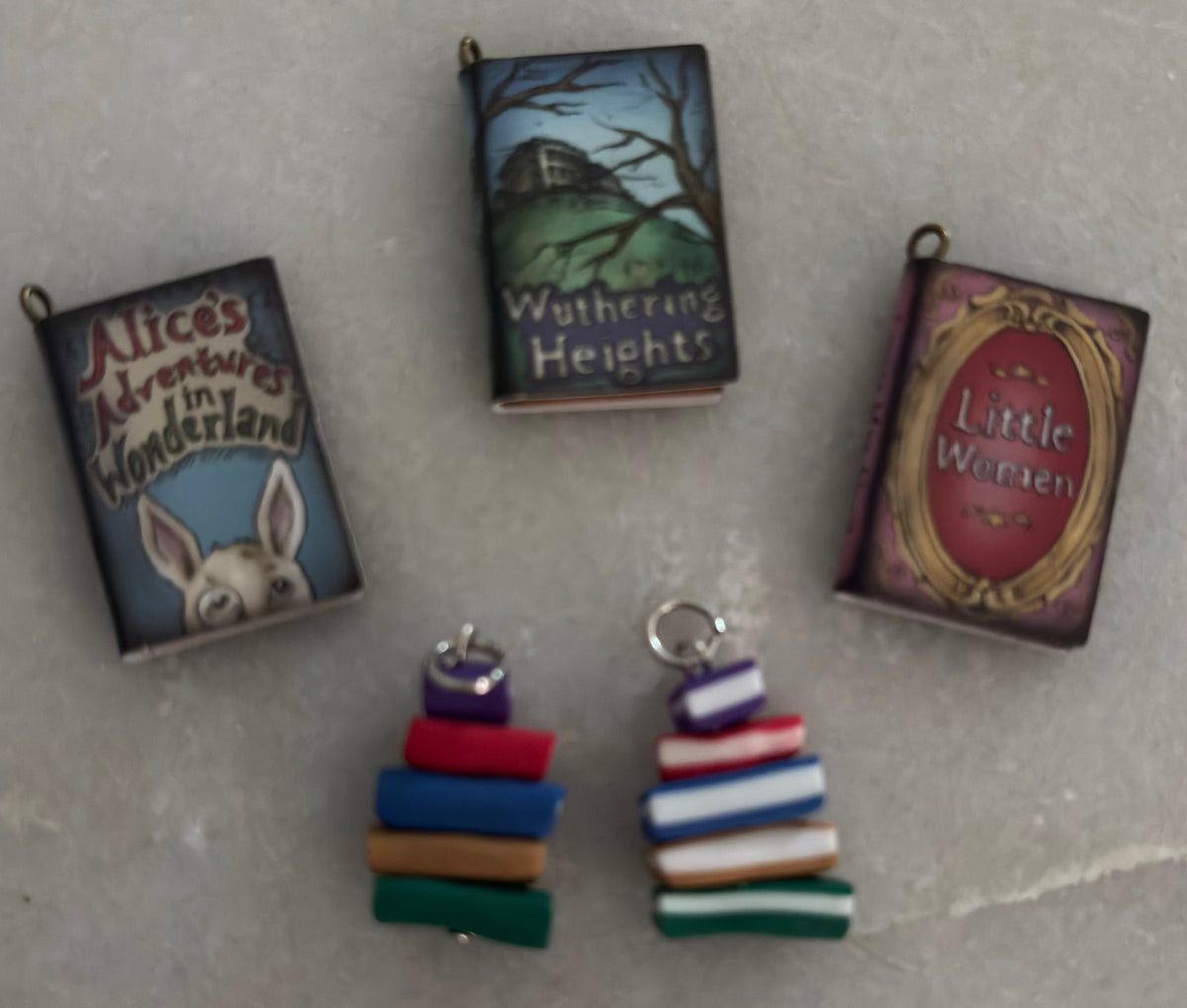 Miniature book charms on a gray surface