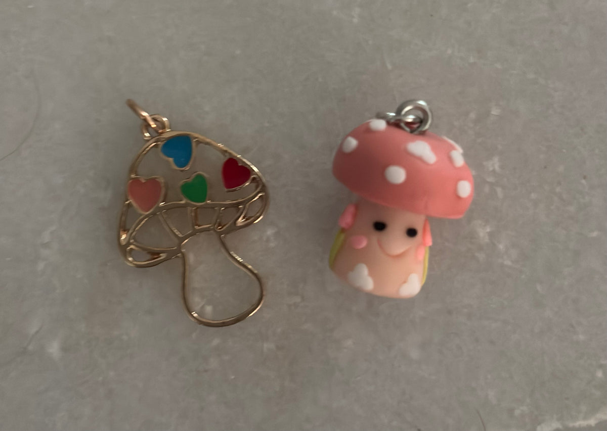 Two mushroom-shaped charms on a gray surface