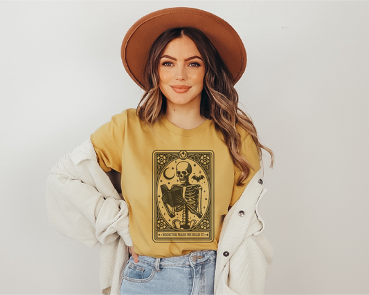 Woman wearing a mustard yellow t-shirt with a graphic design, standing against a plain background