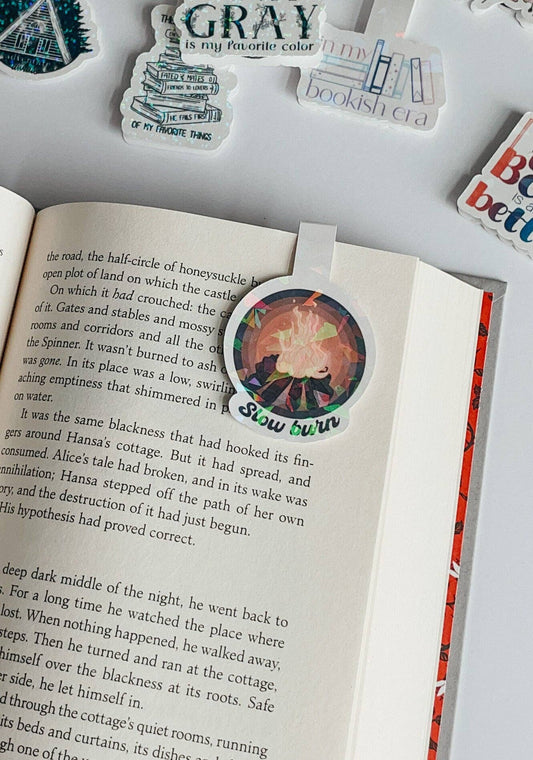 Book with a sticker on it, surrounded by other stickers on a white surface