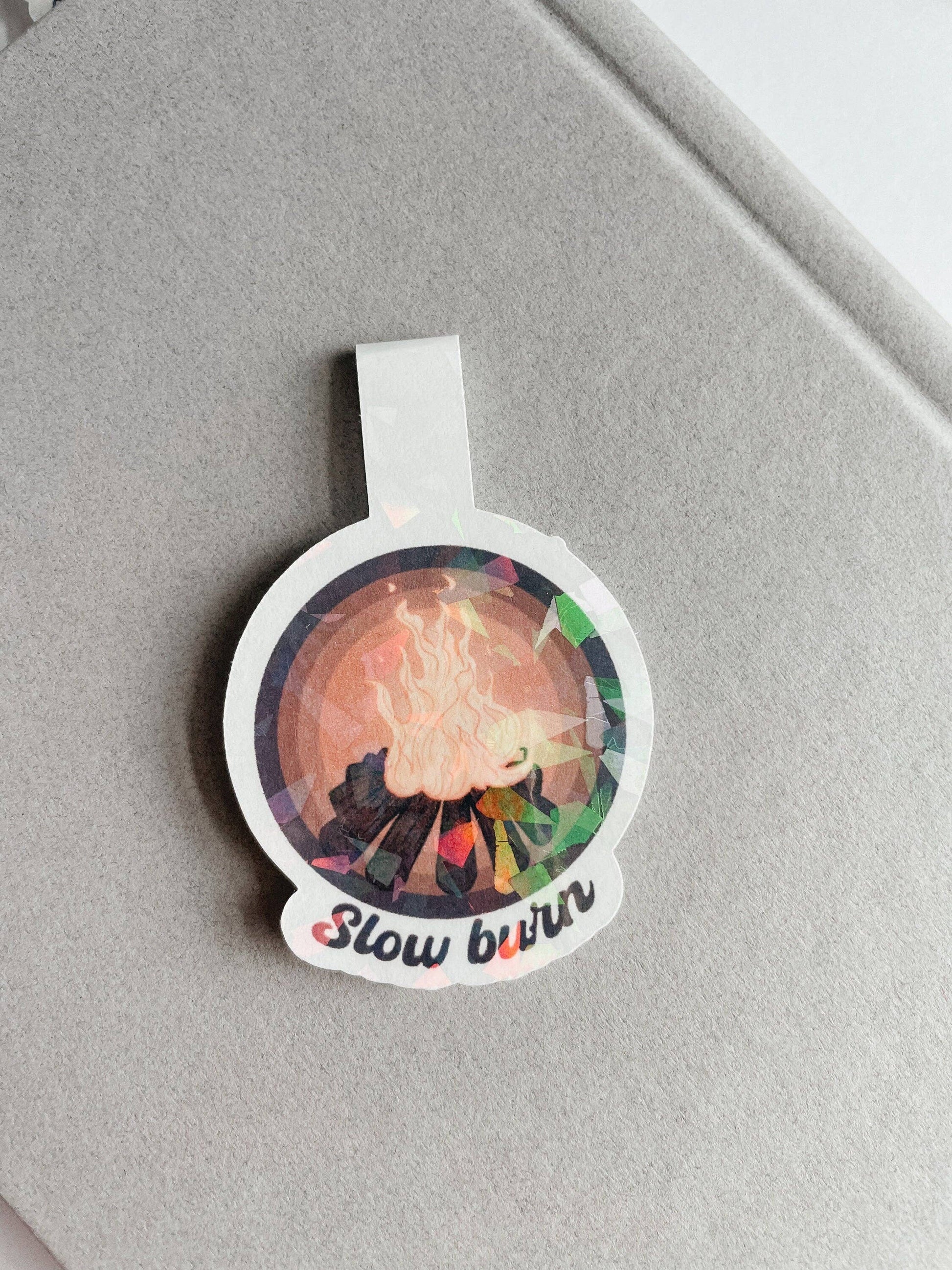 Round sticker with colorful design and 'Slow burn' text on a gray background
