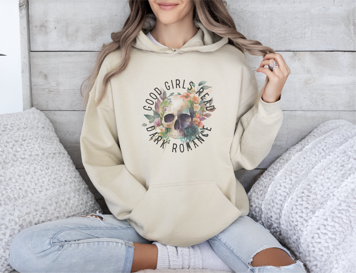 Person wearing a beige hoodie with a skull design and text, sitting on a textured surface.