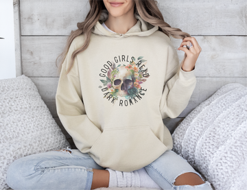 Person wearing a beige hoodie with a skull design and text, sitting on a textured surface.